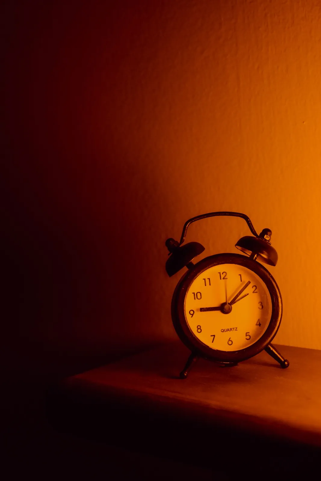 An old analog alarm clock in warm, low light