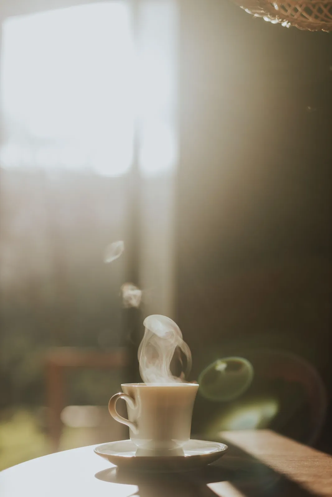 A steaming cup of coffee on a table in a sunny café