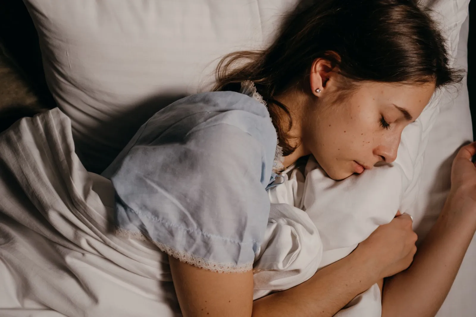 A young woman sleeping on a white pillow at night