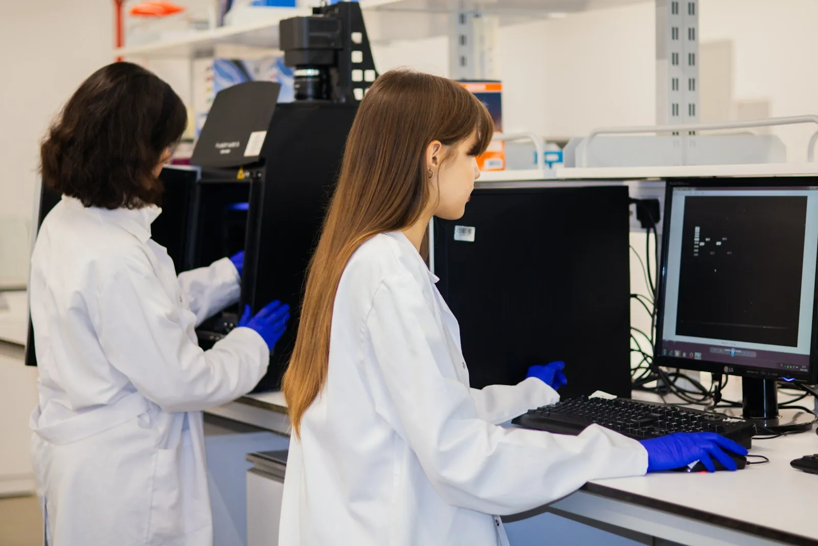 Two scientists working side by side at computers in a laboratory