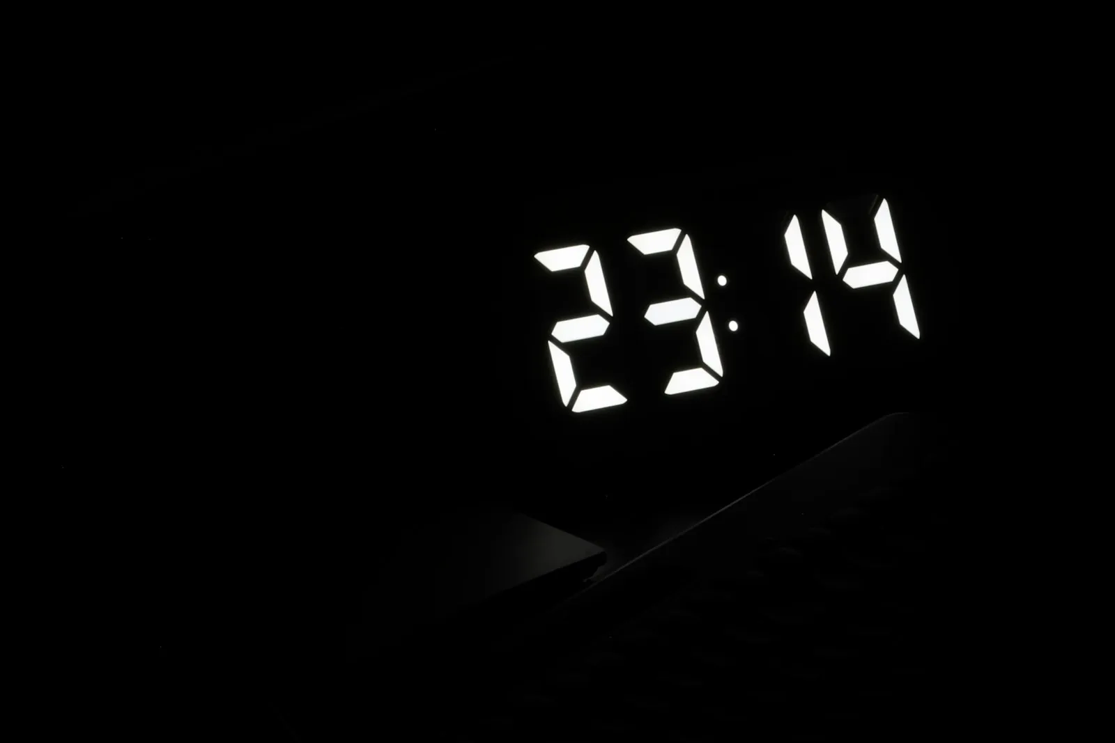 A digital clock glowing in a dark room late at night