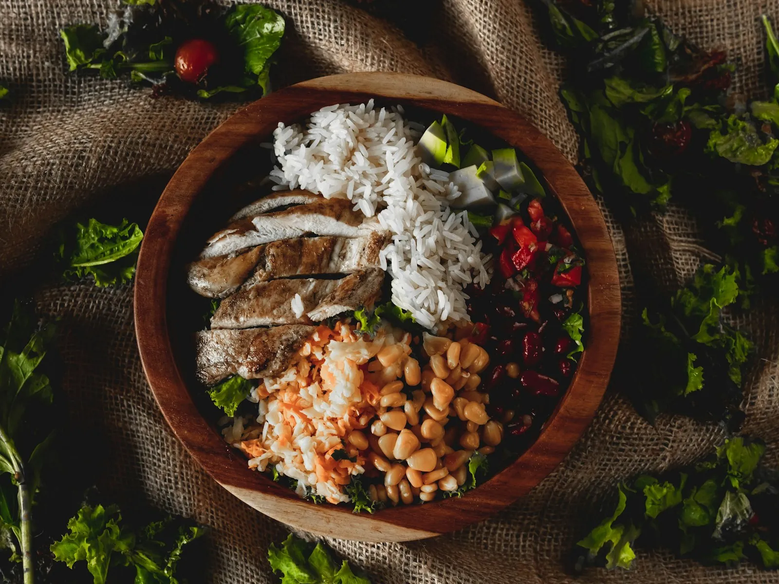 A wooden bowl filled with chicken, rice and beans