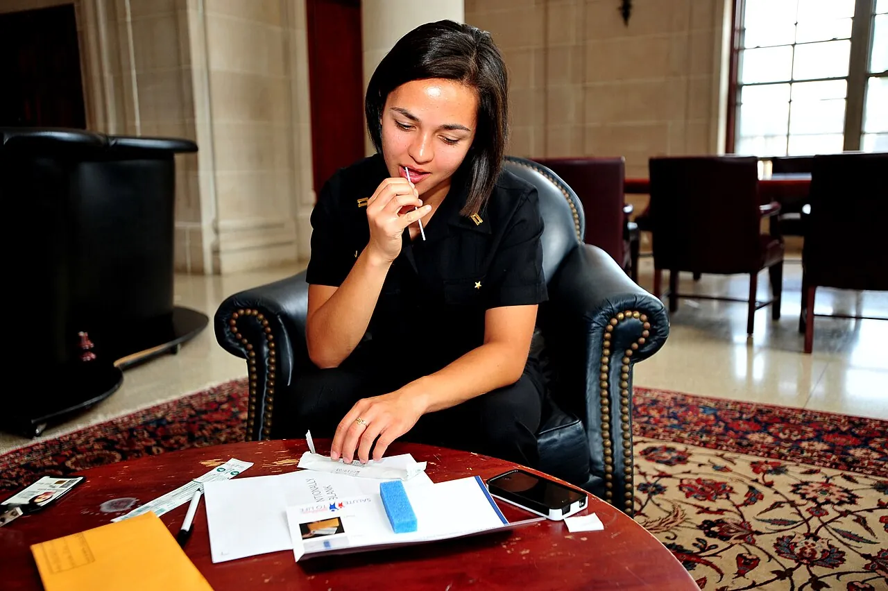 A young woman swabs the inside of her cheek for a DNA test