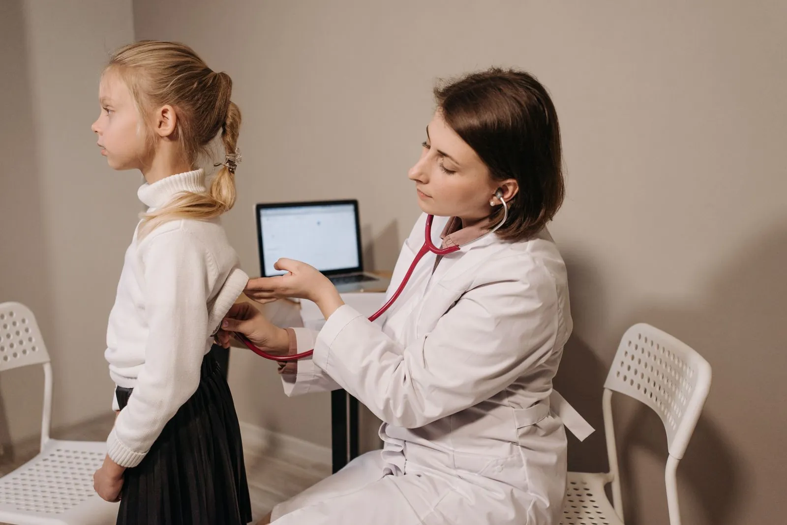 Doctor listening to a young child's breathing with a stethoscope during a checkup in a clinic