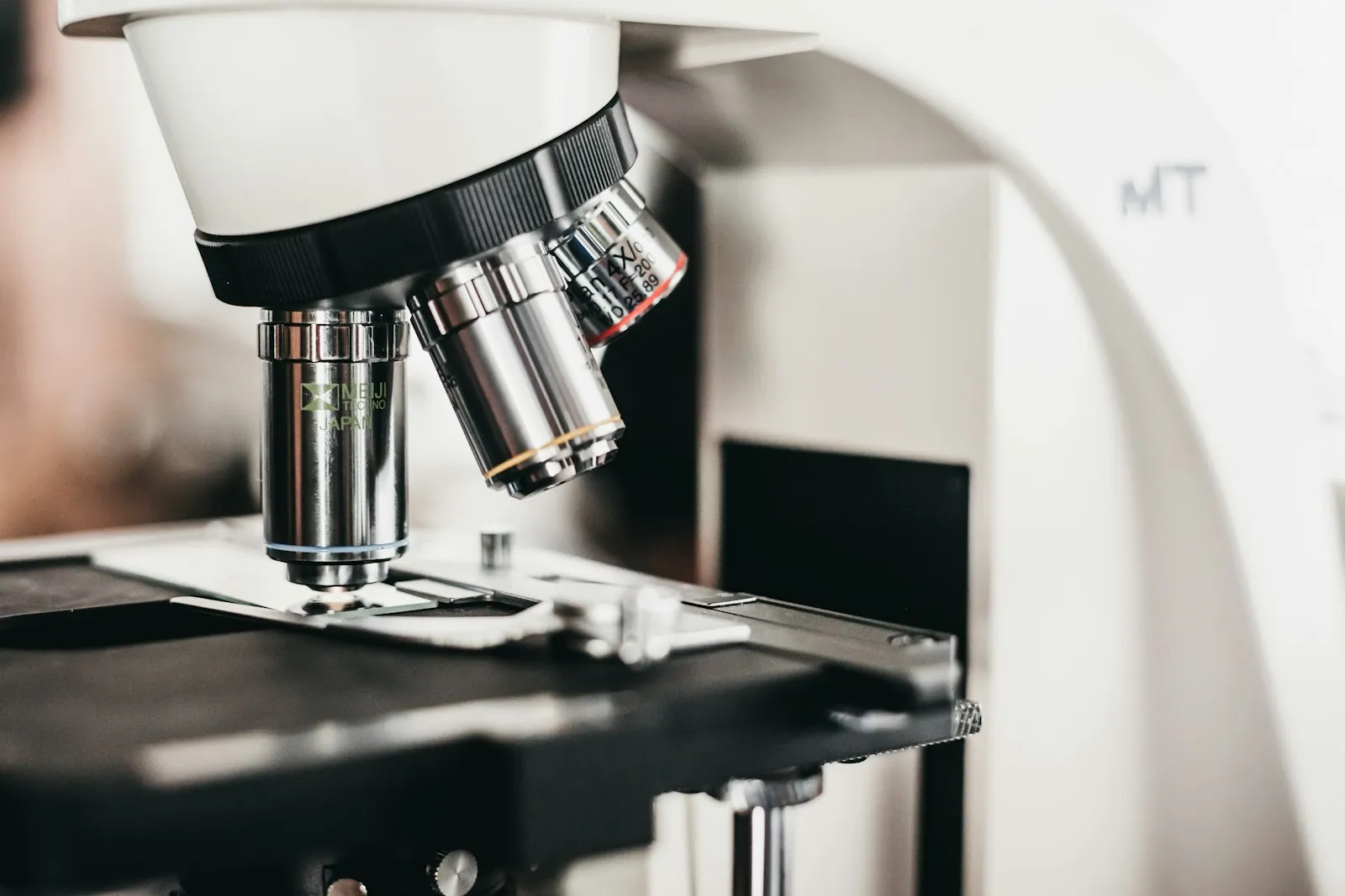 Close-up of a lab light microscope with several objective lenses turned toward the slide stage