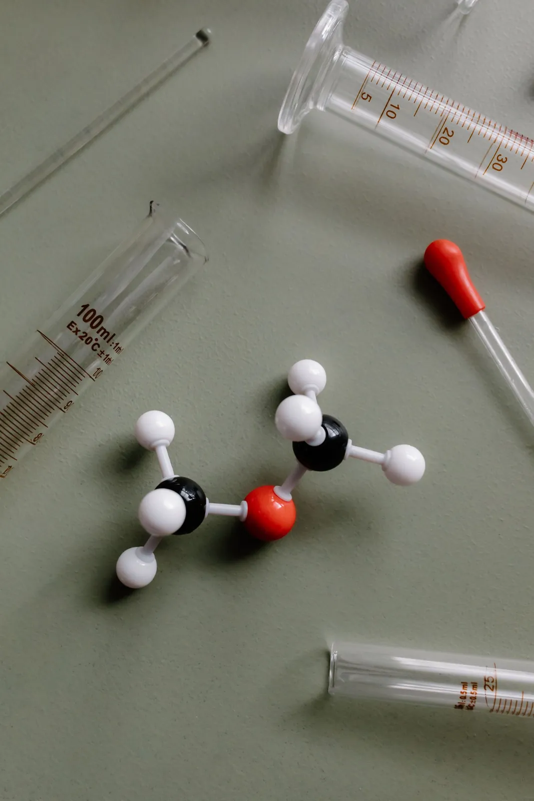 A plastic molecule model next to pipettes and test tubes in a lab