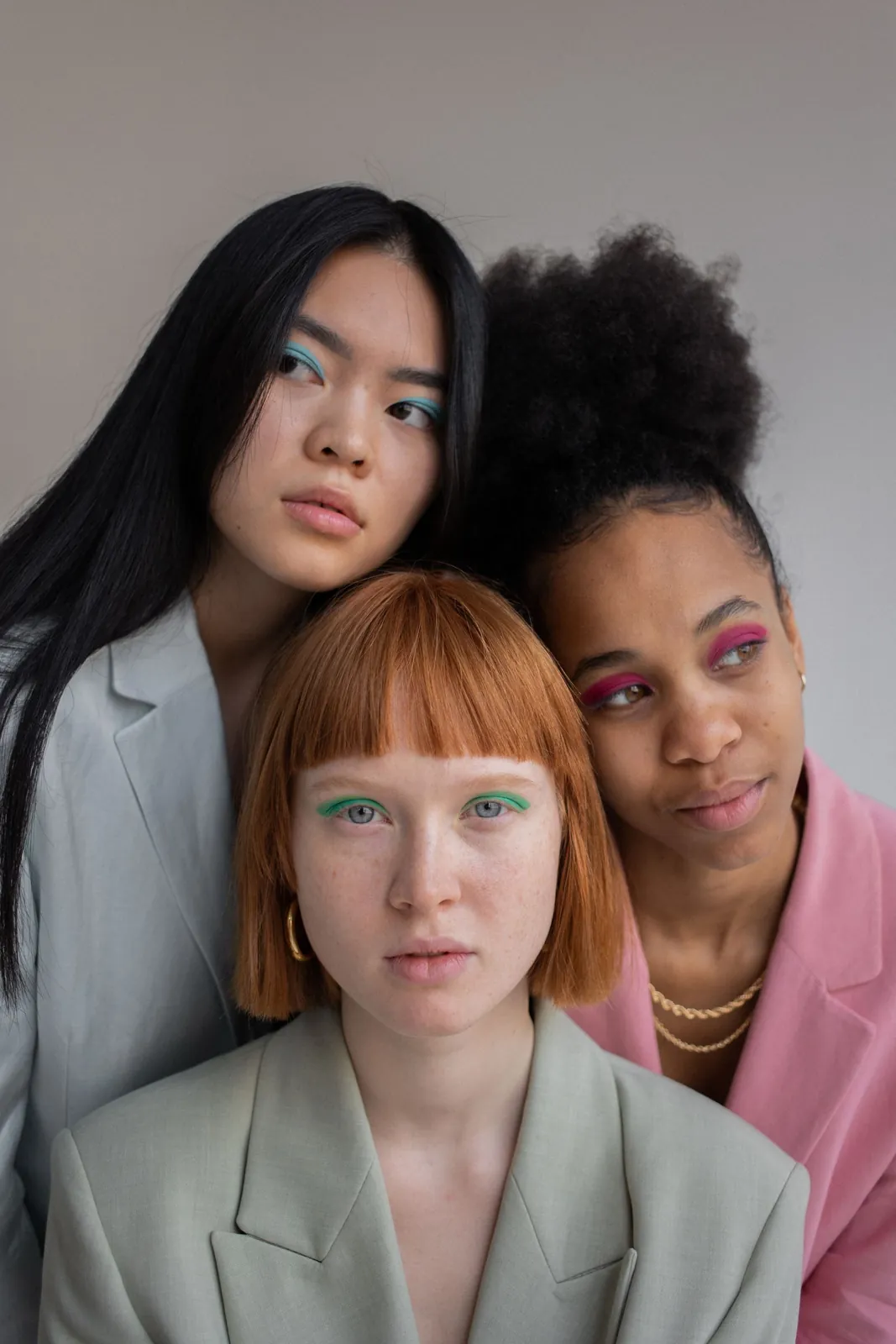 Three young women in blazers, a woman with red hair in front of two women with dark hair