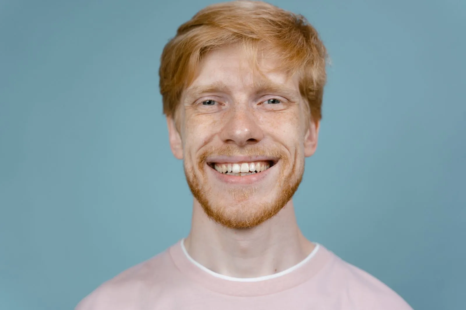 A smiling man with red hair against a blue background