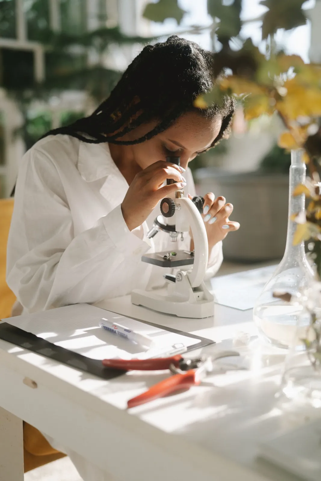 A woman scientist in a lab coat looking into a microscope