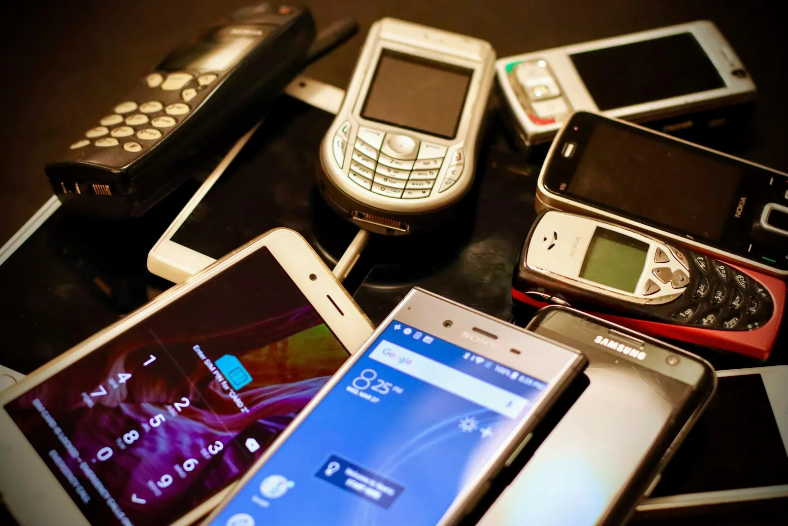 A pile of old and new cell phones in many colors