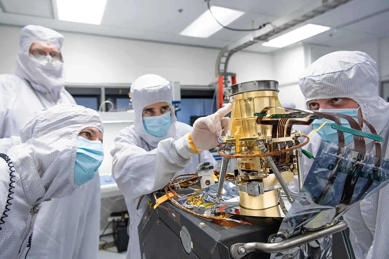 Engineers in a clean room at NASA’s Jet Propulsion Laboratory check an imaging instrument made for a satellite