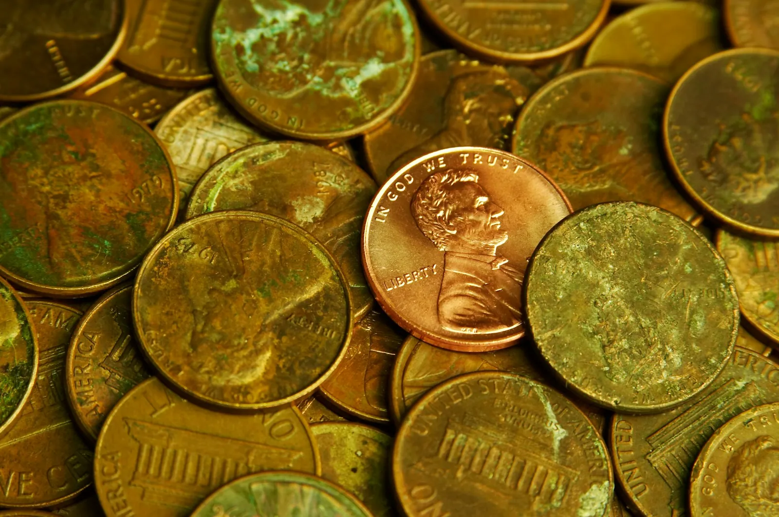 A shiny new penny on a pile of older, worn pennies
