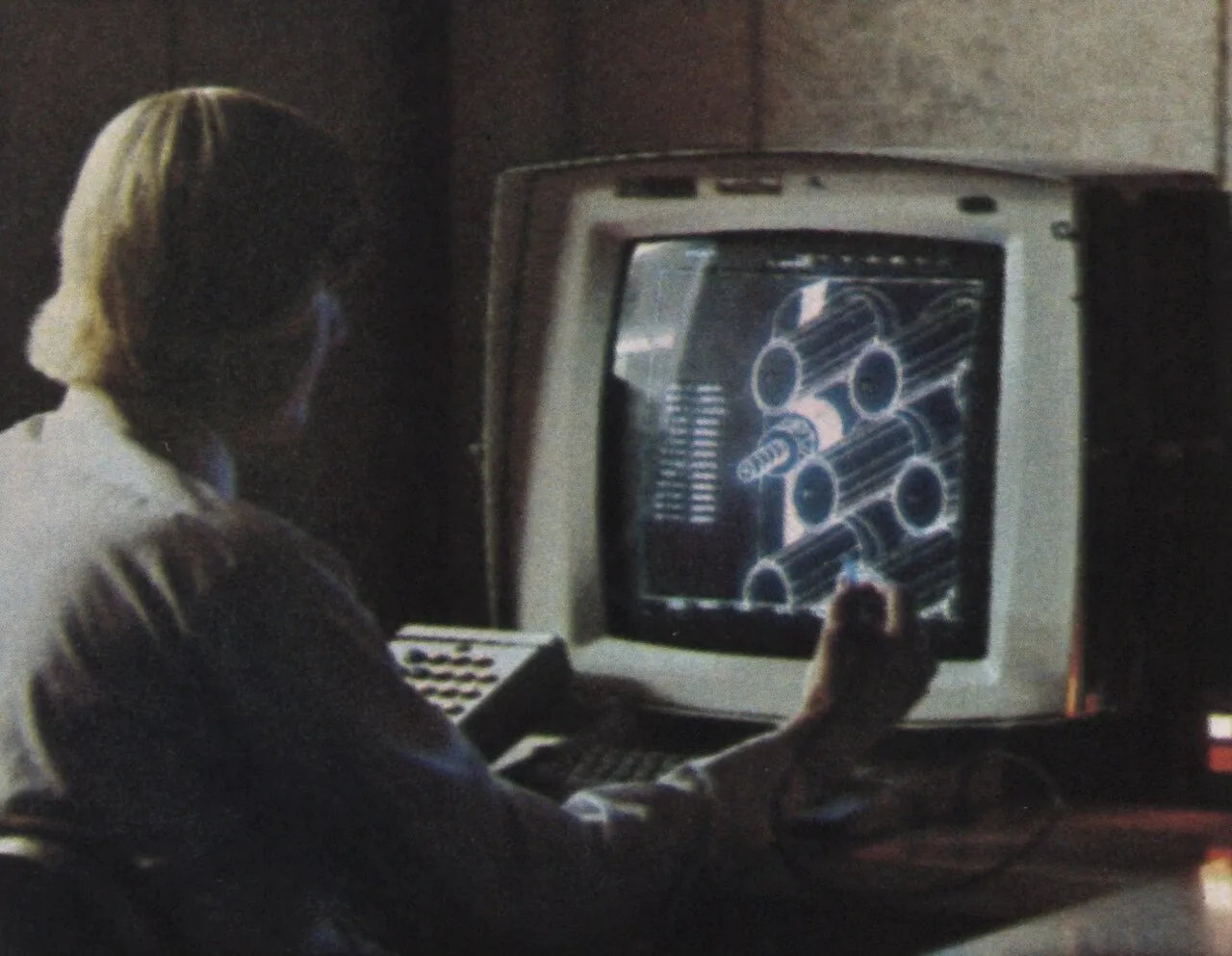 An engineer works at a computer design station with a light pen in hand