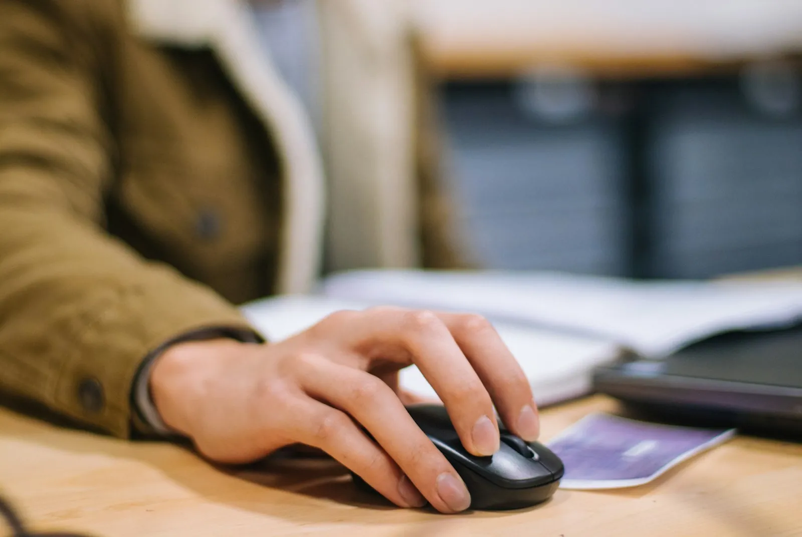 A hand holding a black wireless computer mouse