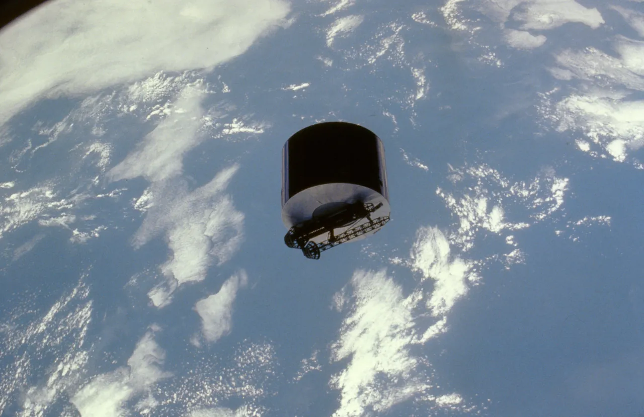 The Syncom IV communications satellite in orbit above Earth