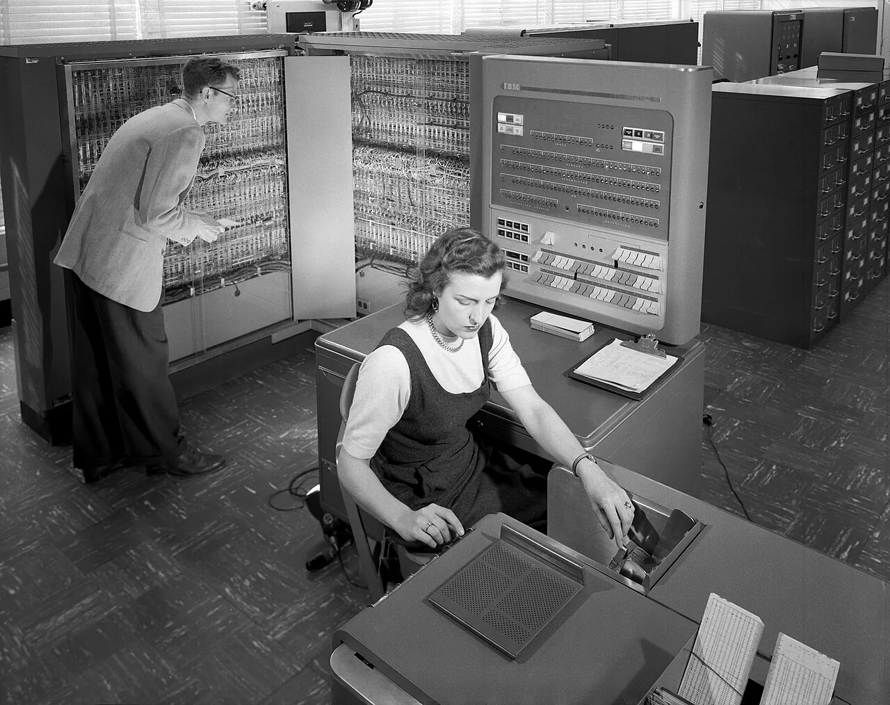 Two workers run a room-sized IBM 704 computer used for aircraft research at Langley, the lab that became part of NASA