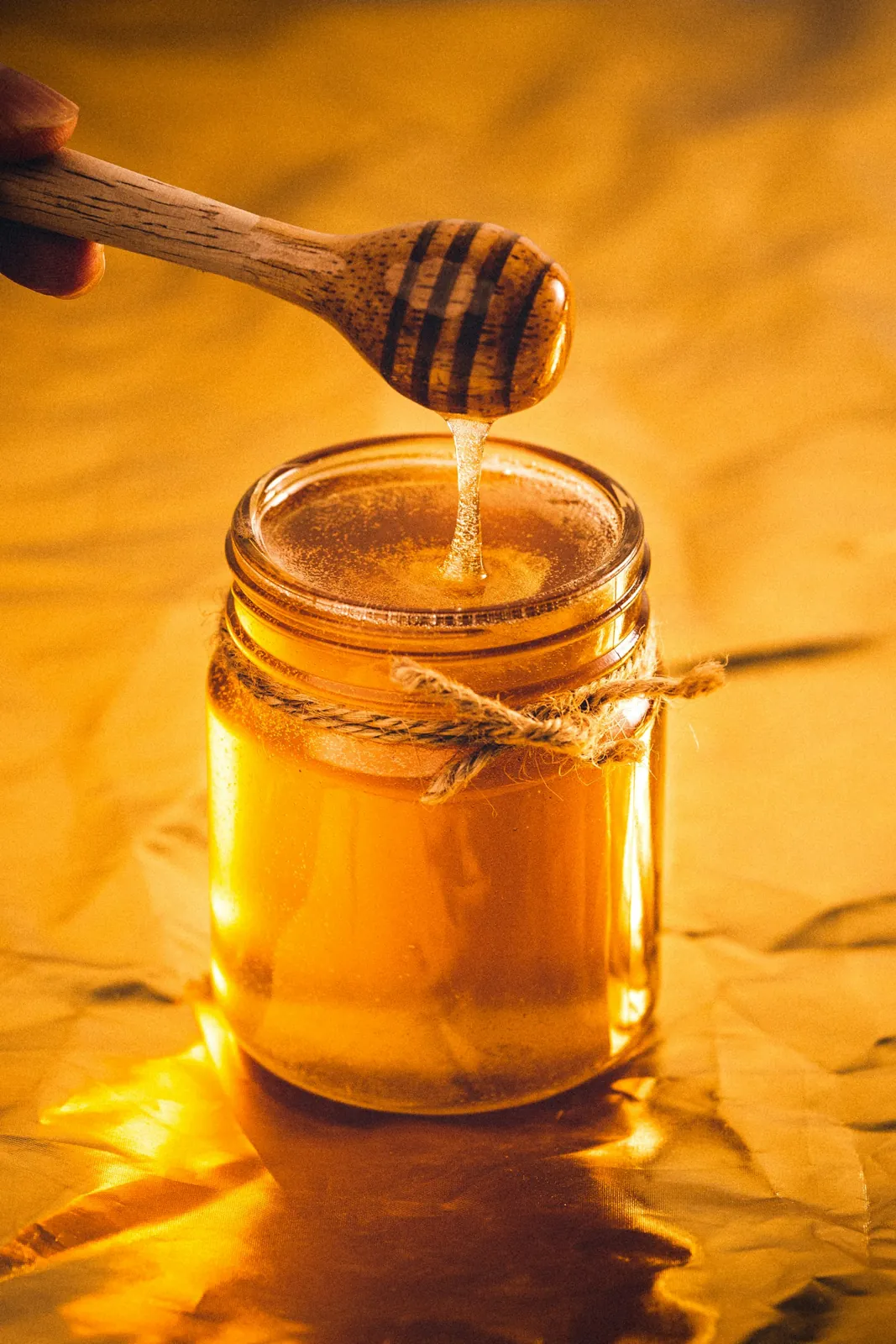 A clear glass jar filled with dark honey