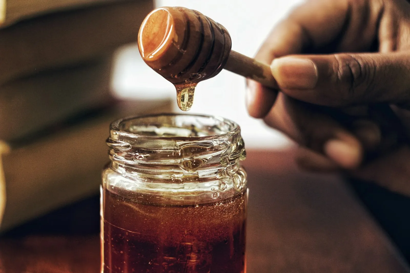 A jar of honey with a piece of honeycomb