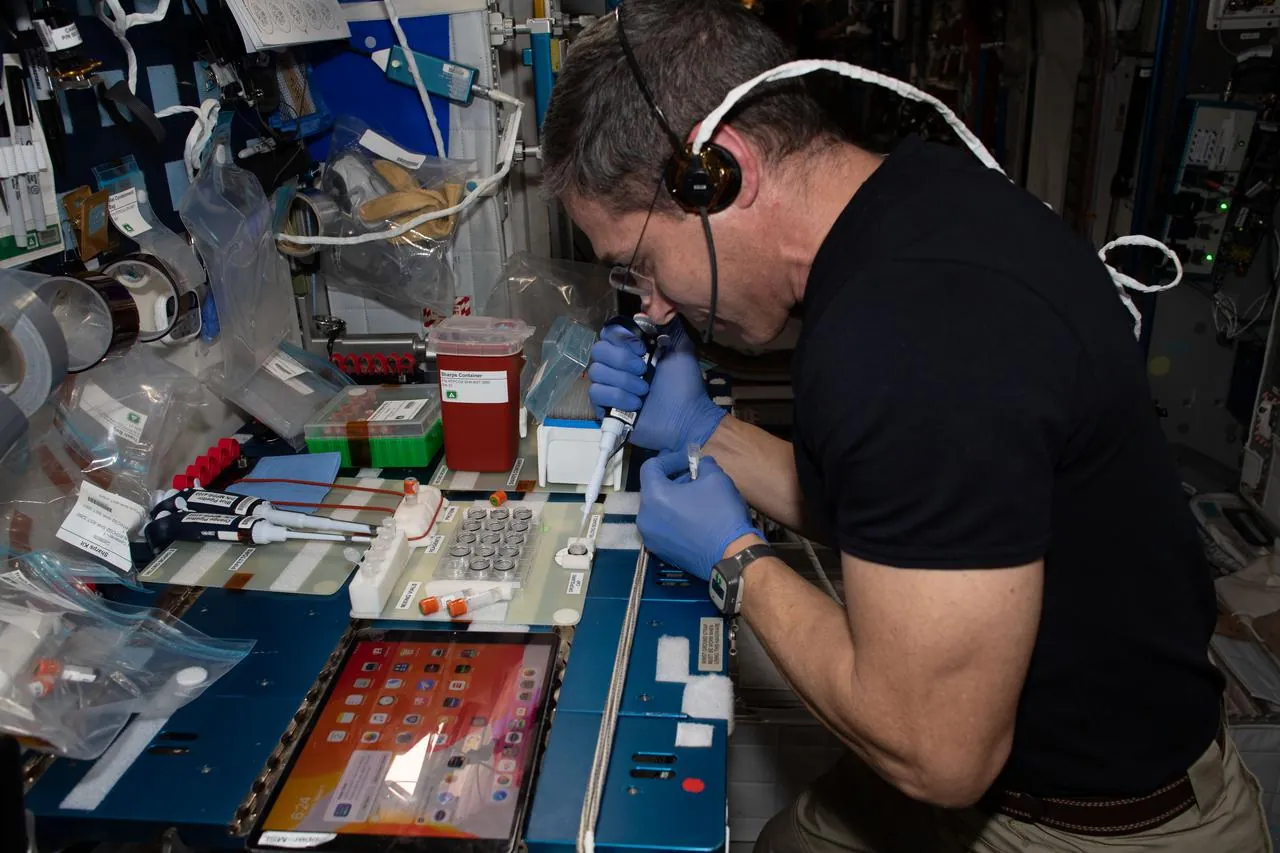 NASA astronaut Michael Hopkins fills protein crystal plates with a pipette on the International Space Station