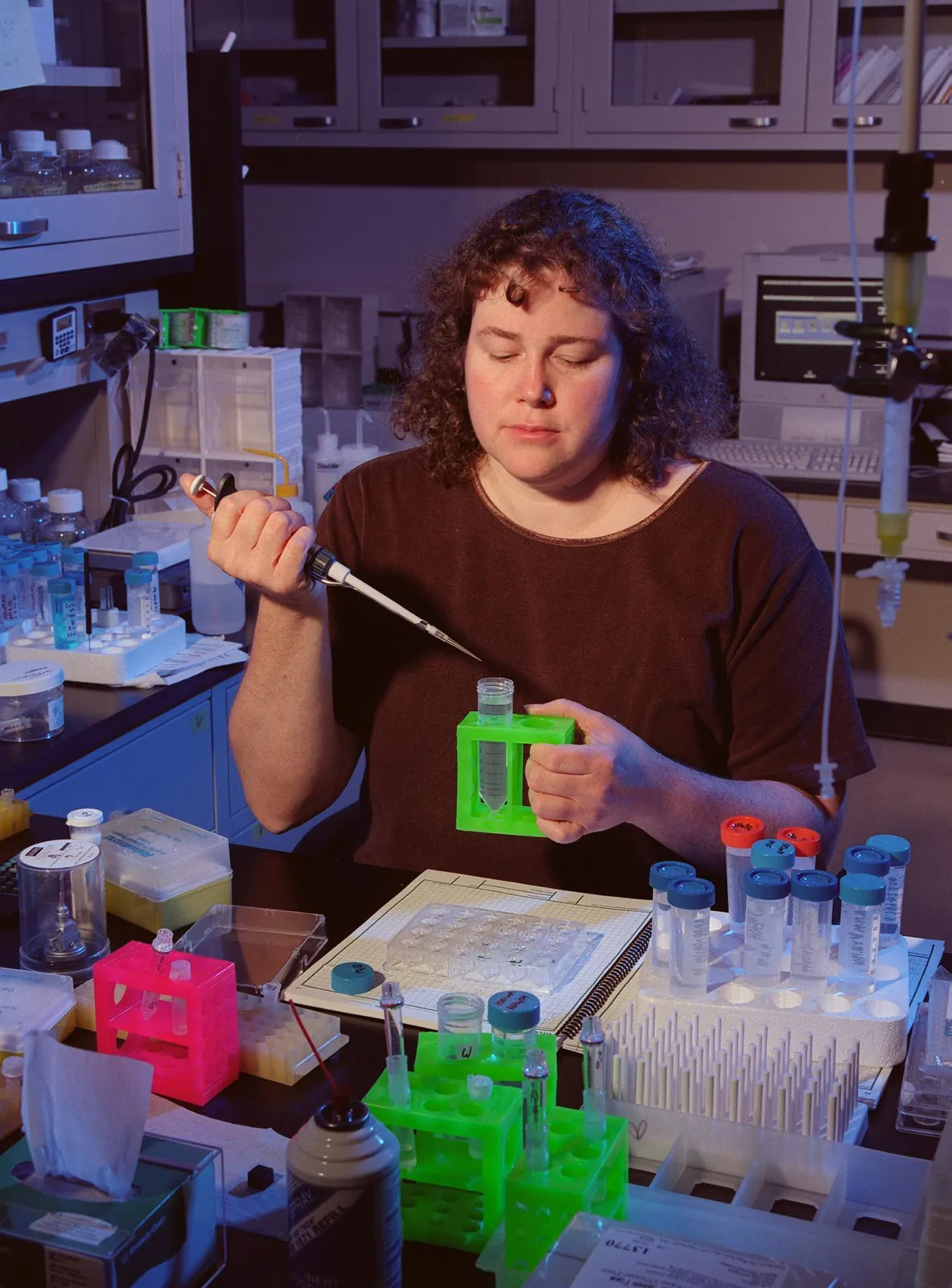 A NASA scientist uses a pipette to add protein solution to a crystal-growing tray at her lab bench