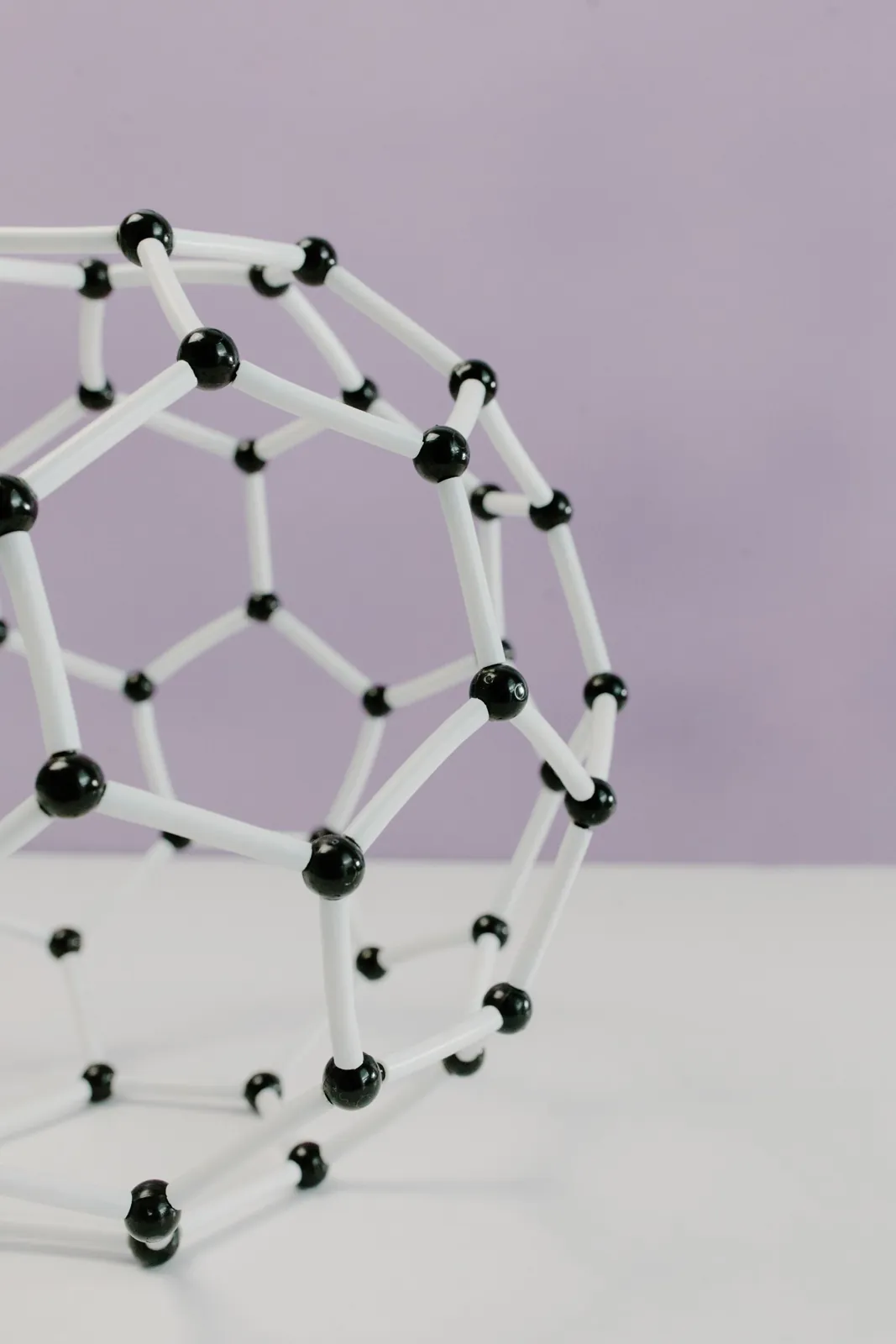 A white and black plastic model of a molecule against a pastel background