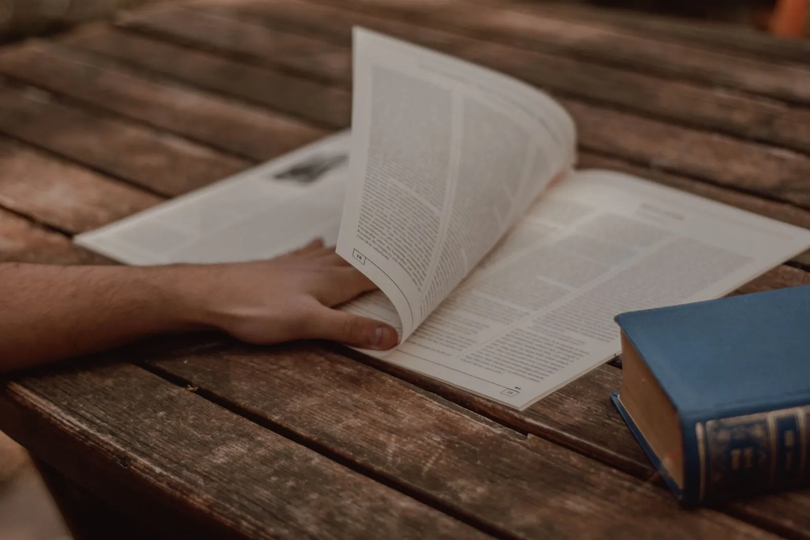 A reader turning the page of a printed article set in columns of text