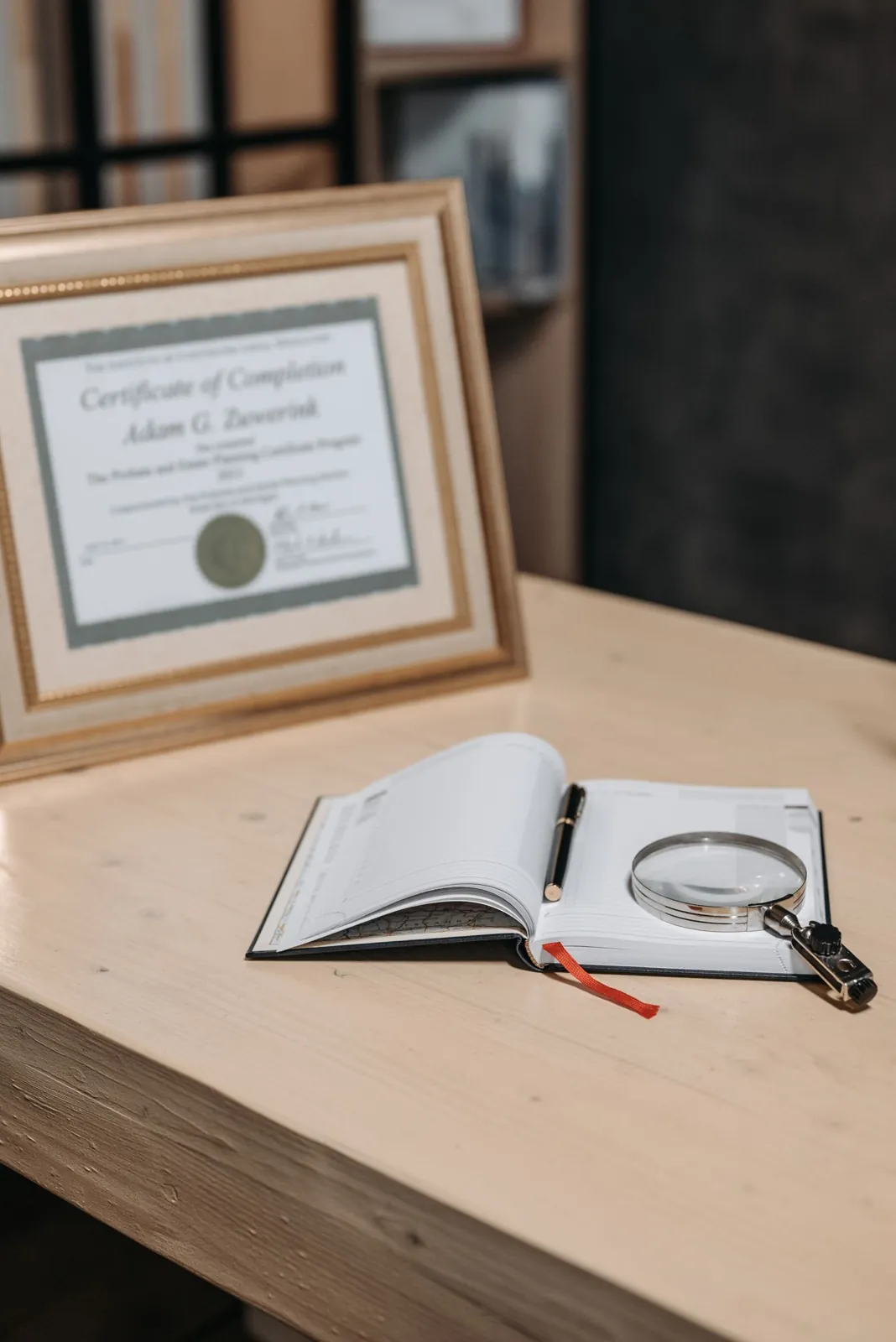 A magnifying glass resting on an open notebook on a wooden table