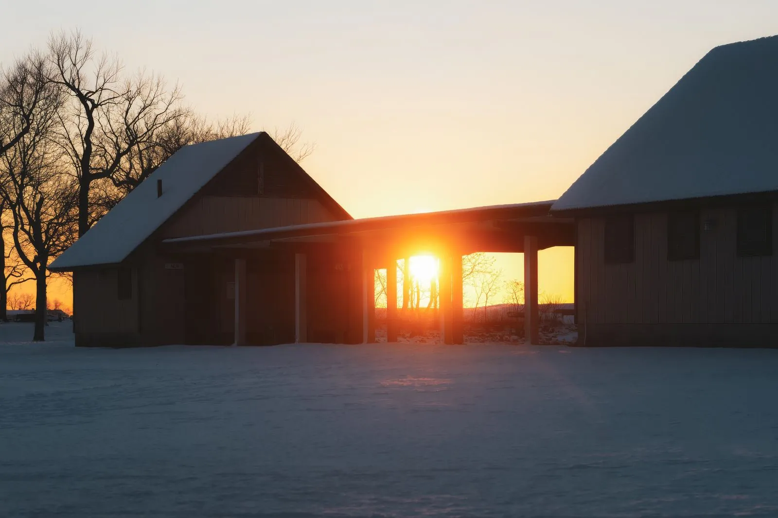 The winter sun rising low behind snow-covered buildings
