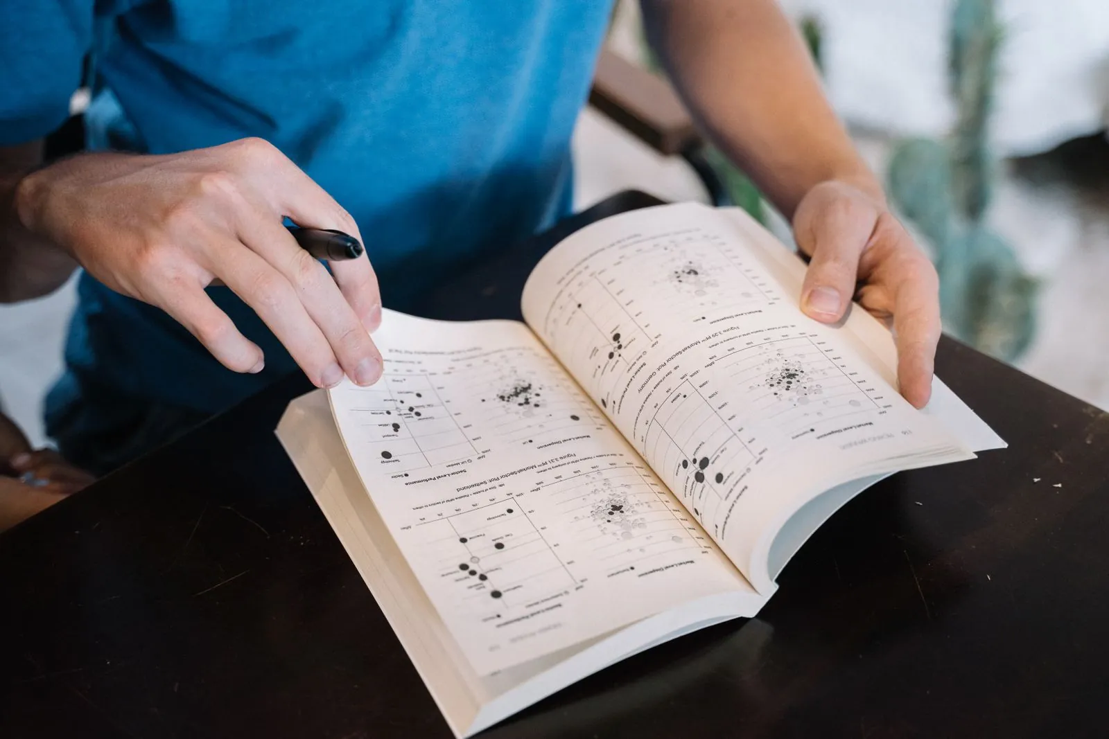 Hands turning the pages of a textbook full of scientific graphs