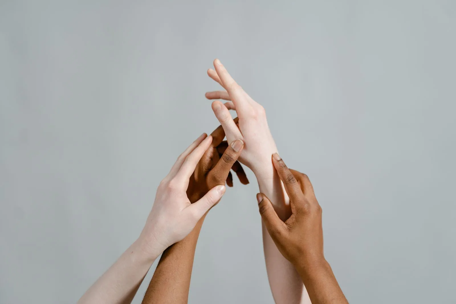 Hands with different skin tones reaching in toward each other