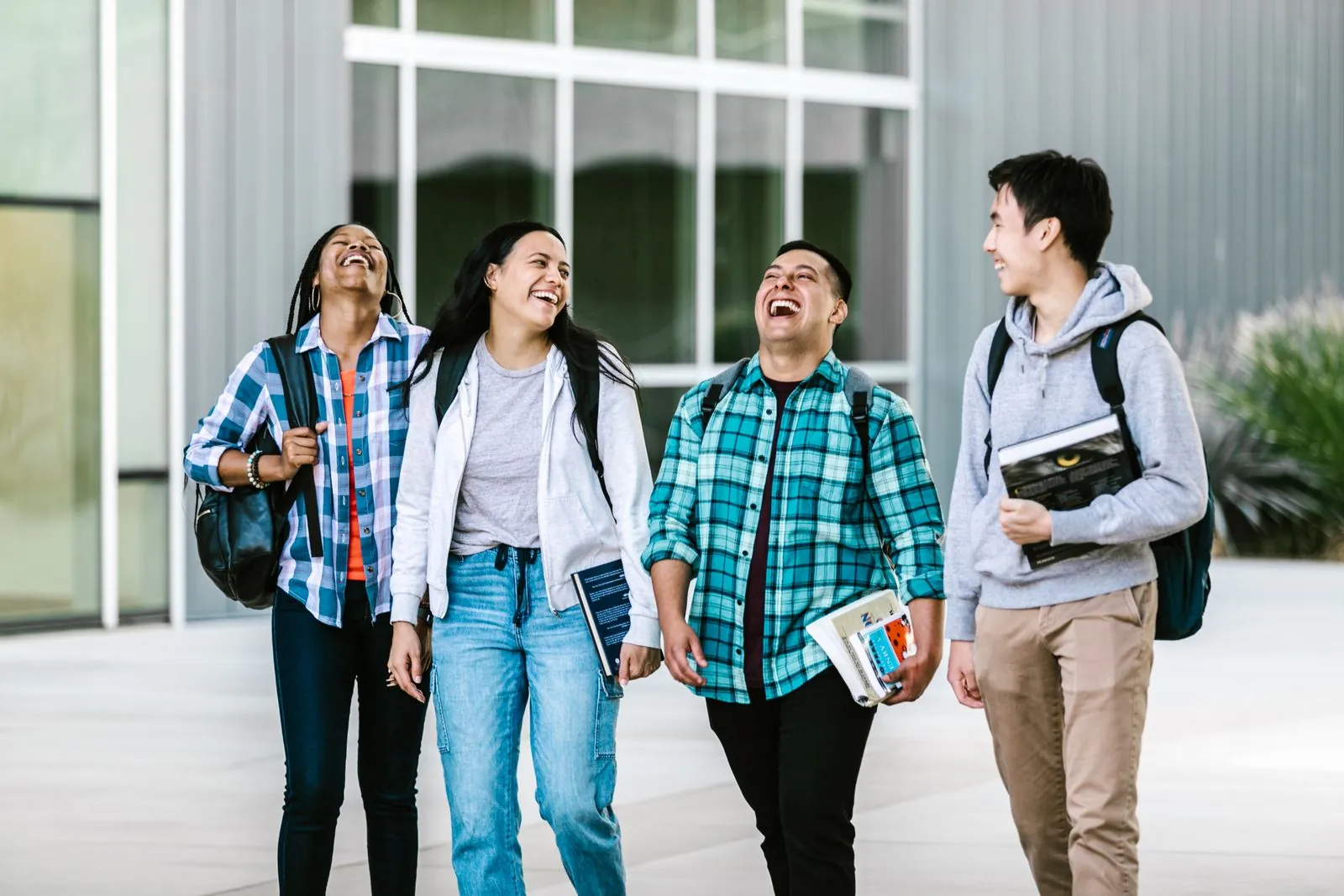 College students with a range of skin tones laughing as they walk together on campus
