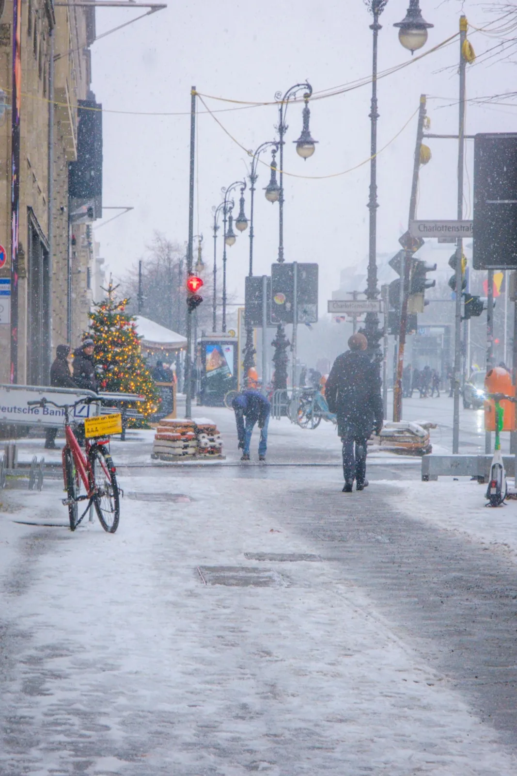 People walking along a snowy street in Berlin, Germany, decorated for the winter holidays