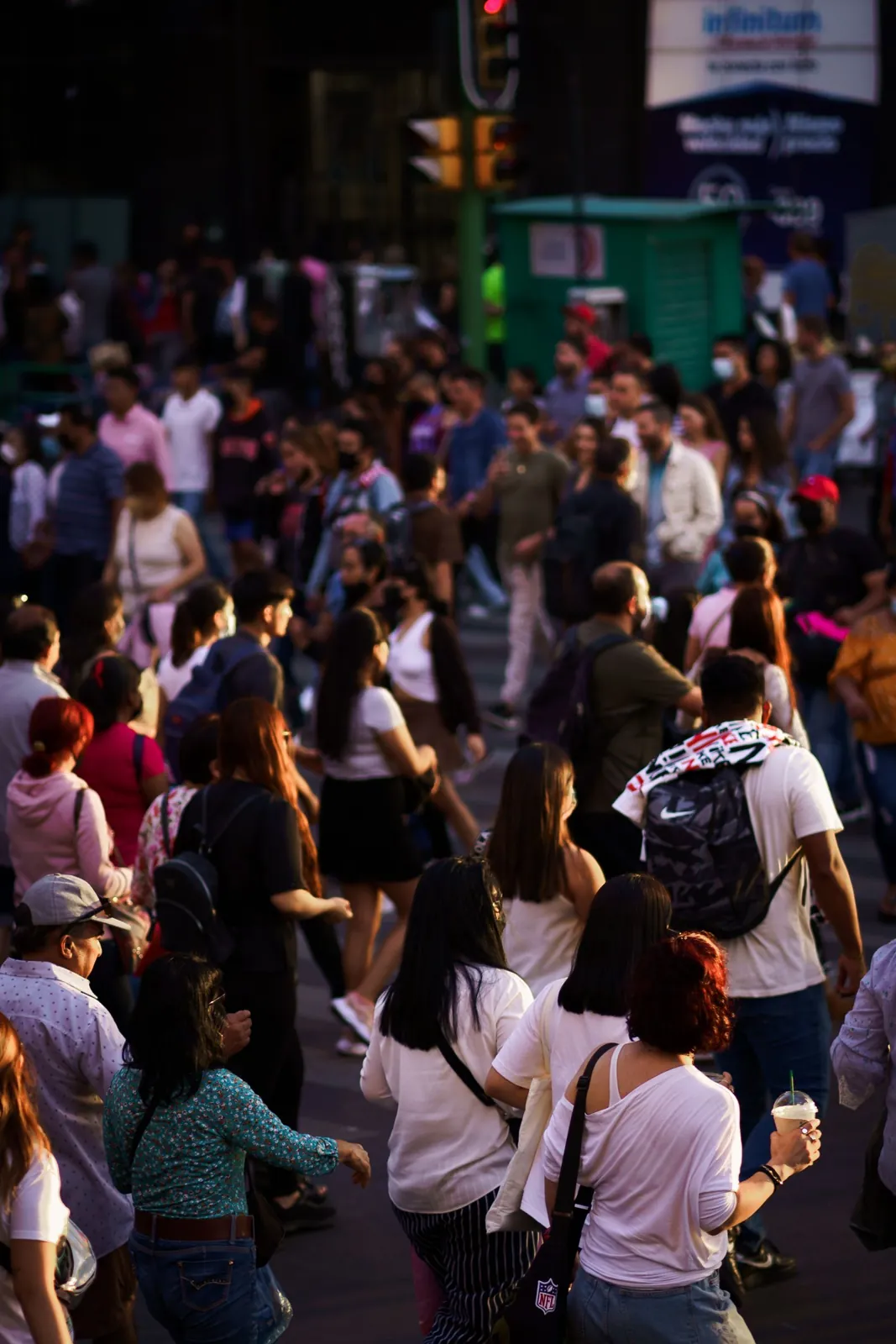A crowd of people crossing a busy city intersection