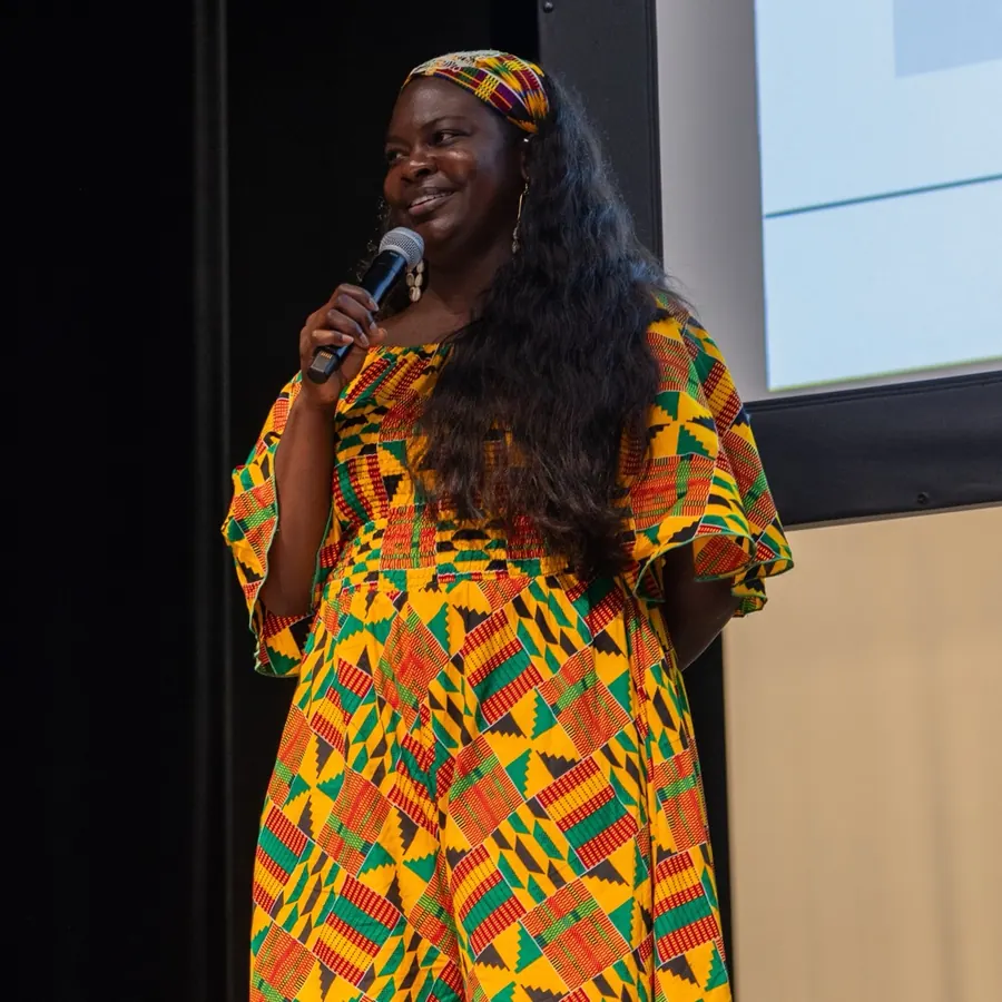 Dr. Raven Baxter speaking on stage with a microphone