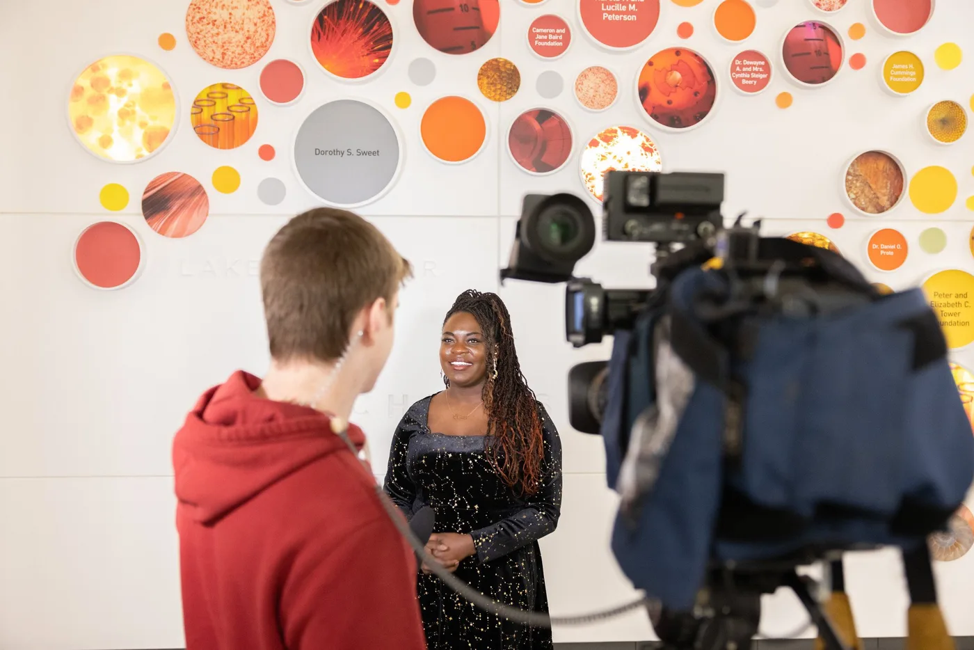 Dr. Raven on camera with a student at a science exhibit