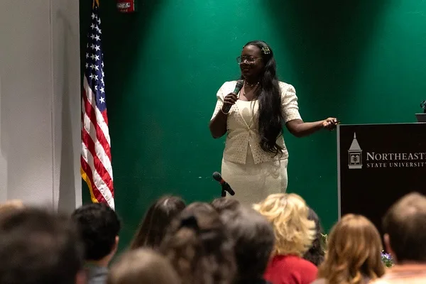 Dr. Raven speaking on stage with a microphone